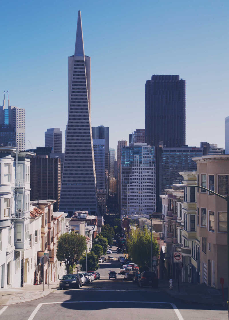 A steep city street leading toward a pointed skyscraper