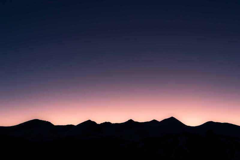 A dark mountain ridge beneath a violet twilight sky