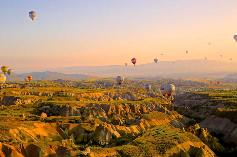 Hot-air balloons above a wide landscape