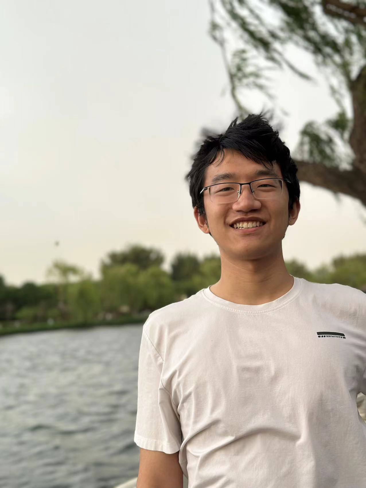 Youyang Du smiling outdoors beside a lake